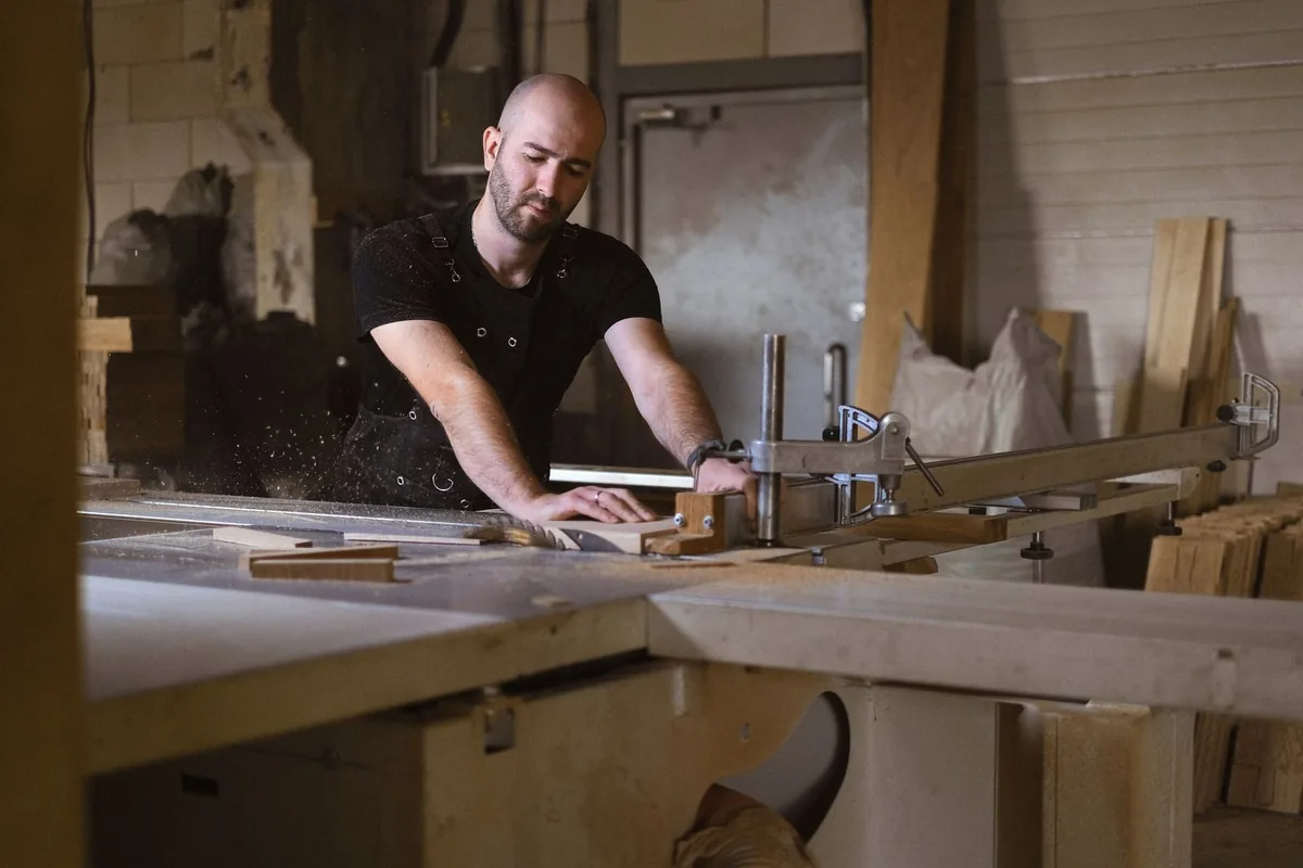 Carpenter cutting a timber panel with a circular saw in a professional joinery workshop