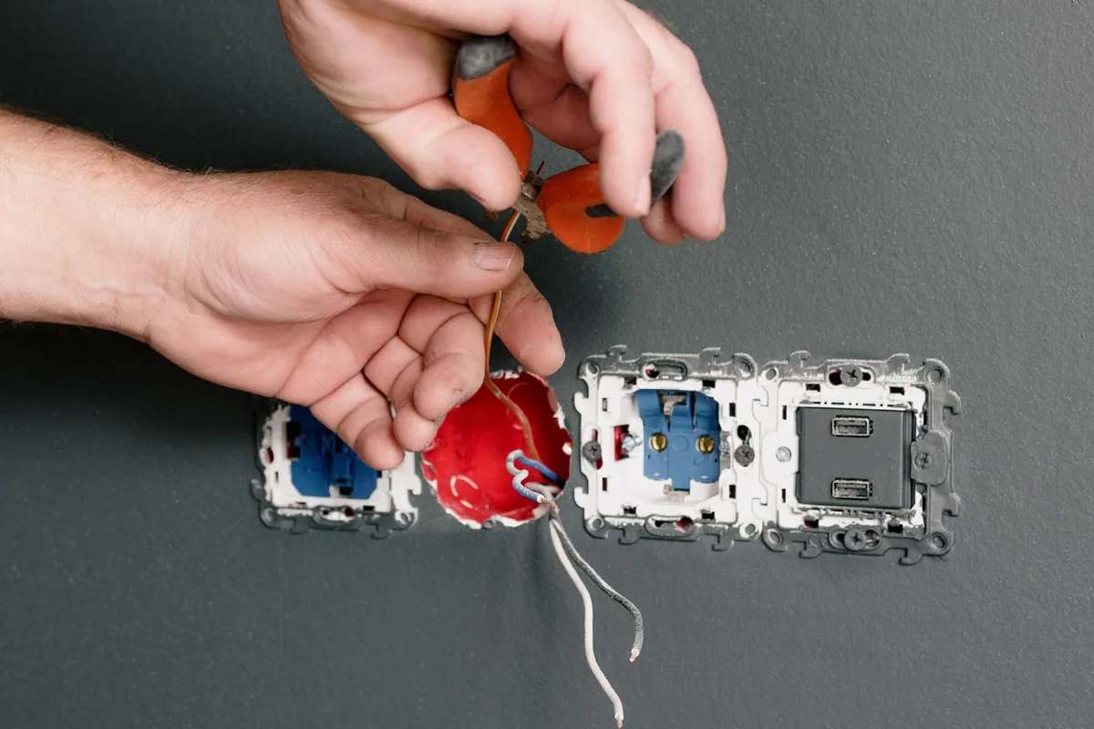 Electrician installing power sockets and switches on a grey wall during an interior electrical fit-out