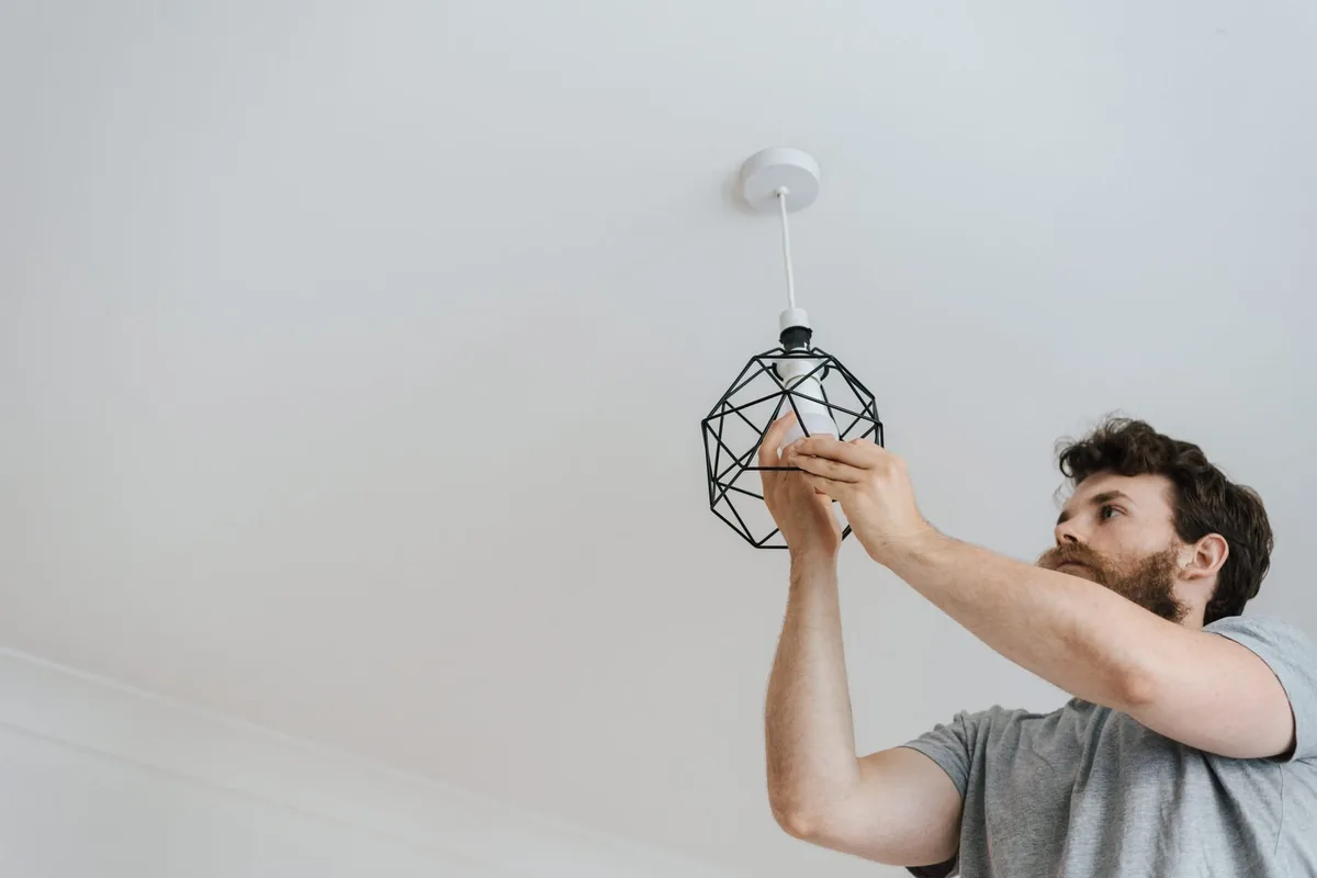 Worker fitting a new ceiling light into place during interior renovation works in an apartment