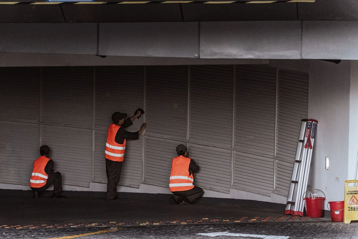 Two workers installing and commissioning roller shutters at an indoor building entrance
