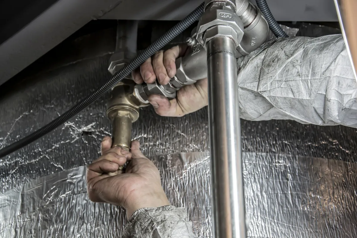 Close-up of a plumber fitting steel supply pipework during a sanitary installation