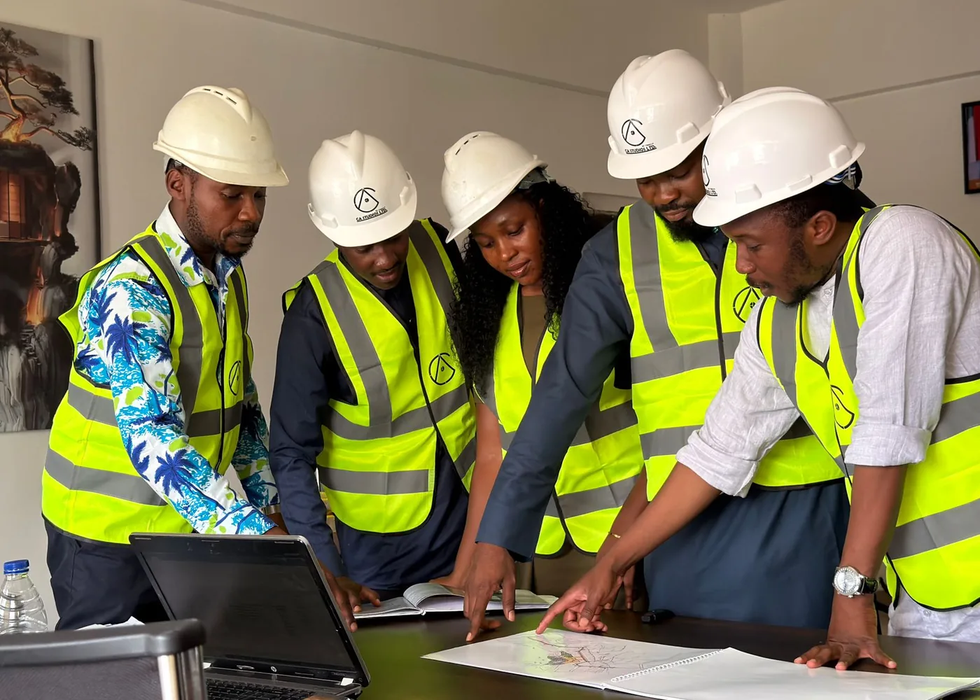 Team of contractors in hi-vis vests and safety helmets reviewing construction plans together on site