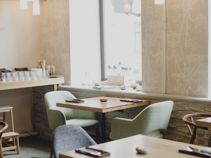 Modern cafe interior with timber tables and chairs beside a large window after a retail fit-out