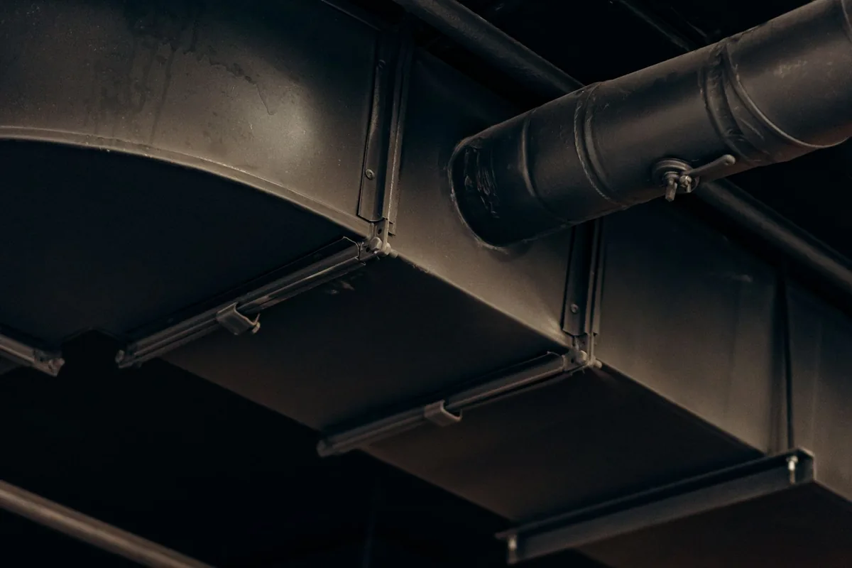 Galvanised ventilation ductwork running above an exposed ceiling in a commercial building