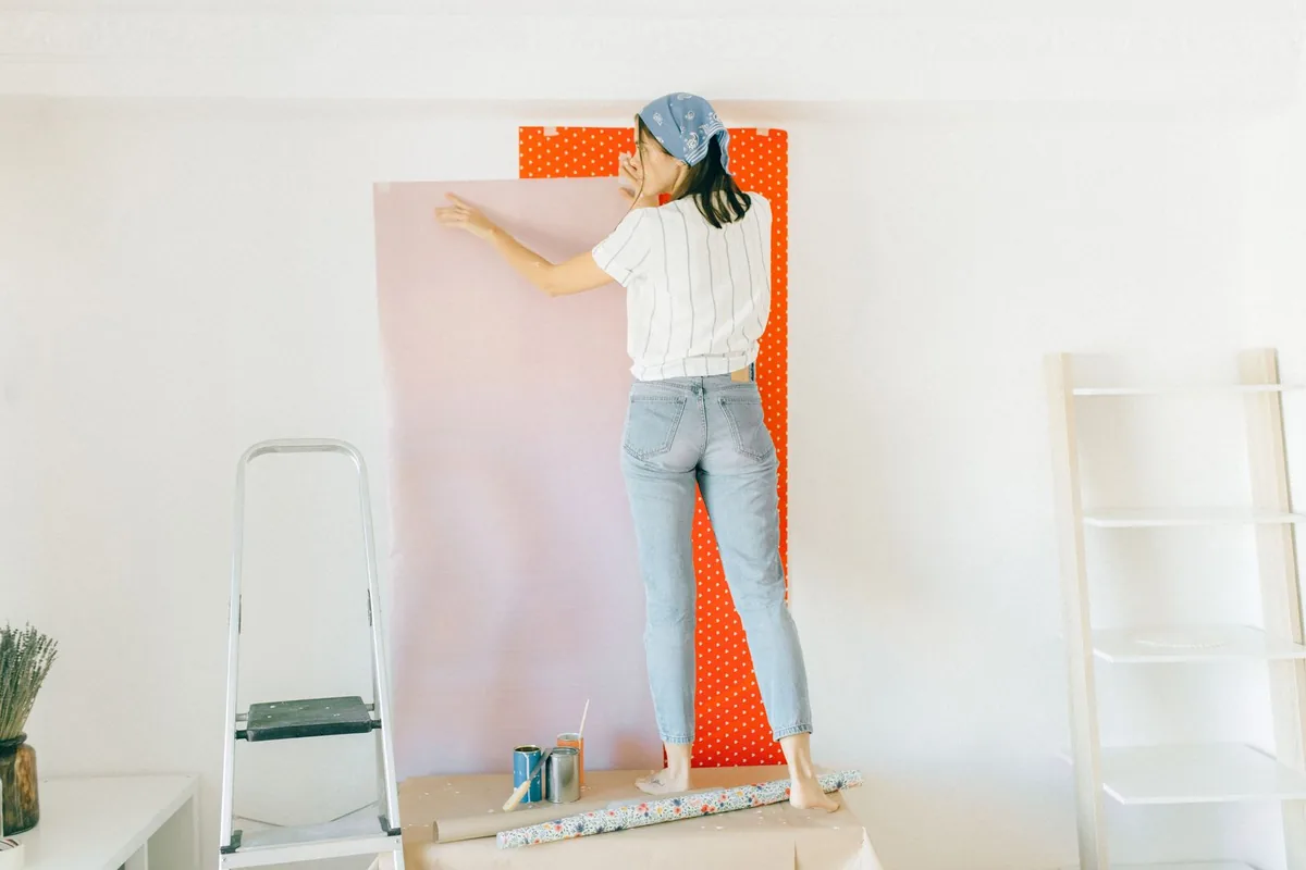 Worker smoothing a length of wallpaper onto an interior wall during a decorating job